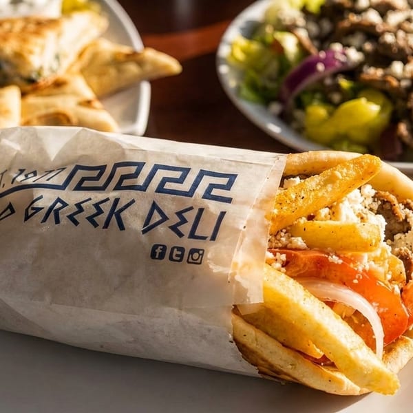 Mad Greek Deli gyro with fries, tomatoes, onions, and feta, alongside a Greek salad.